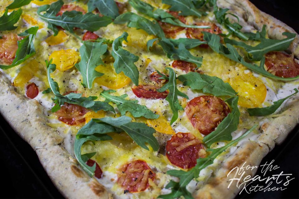 White Pizza mit Knoblauch-Kräuter-Pizzateig, Tomaten, Rucola und einer ...